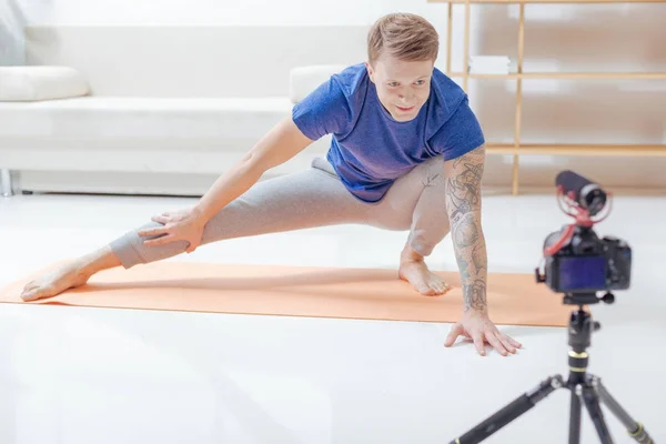 Blogger atento mirando directamente a la cámara mientras graba una lección de yoga — Foto de Stock