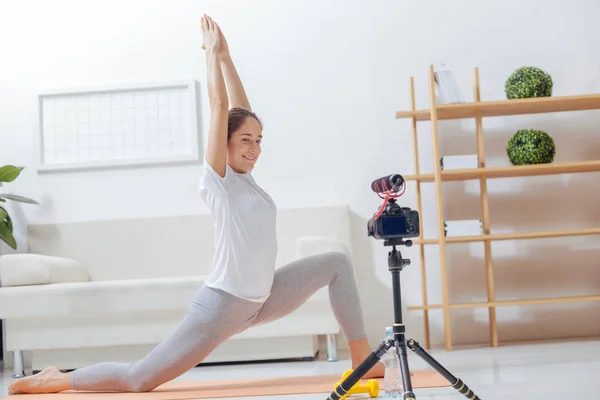 Happy yoga teacher recording her exercises for a video blog and smiling