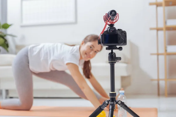 Усміхнений блогер дивиться на камеру, згинаючись на килимок для йоги — стокове фото
