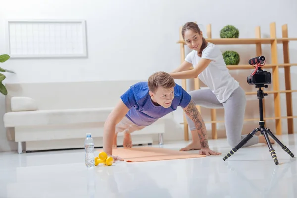 Instrutora alegre tocando as costas de seu assistente enquanto mostra exercícios — Fotografia de Stock