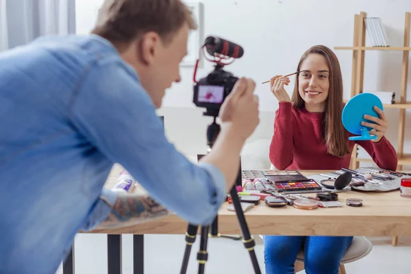 Glückliche Bloggerin schminkt sich, während ihr Freund es aufnimmt — Stockfoto