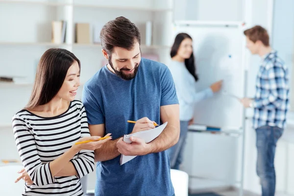 Alegre dos colegas tomando nota de las proposiciones — Foto de Stock