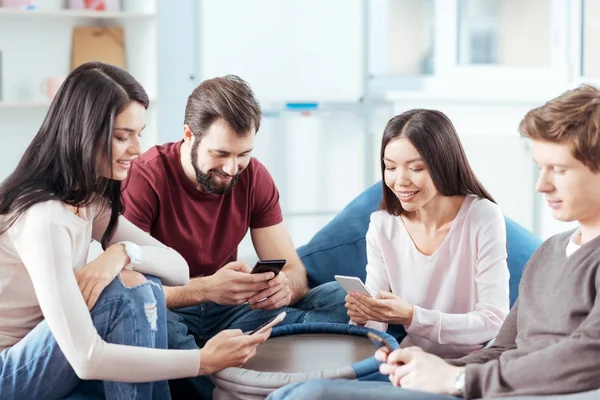 Positivo quattro amici utilizzando i telefoni — Foto Stock