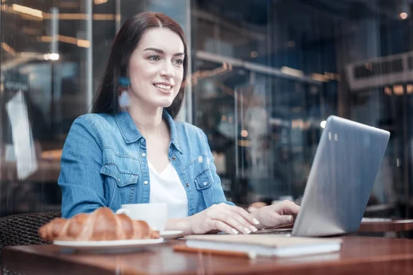 Uppmärksamma brunett tjej som arbetar med sin laptop — Stockfoto