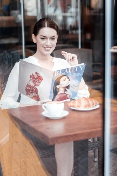 Feliz morena leyendo revista brillante —  Fotos de Stock