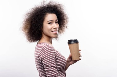 Kahve fincanı tutan sevimli kıvırcık saçlı genç kadın