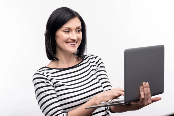 Mooie vrouw in gestreepte trui die op laptop werkt — Stockfoto