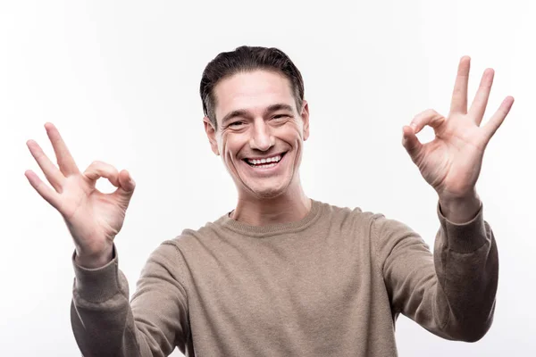 Iloinen mies osoittaa kaksi OK merkkejä ja hymyilee — kuvapankkivalokuva