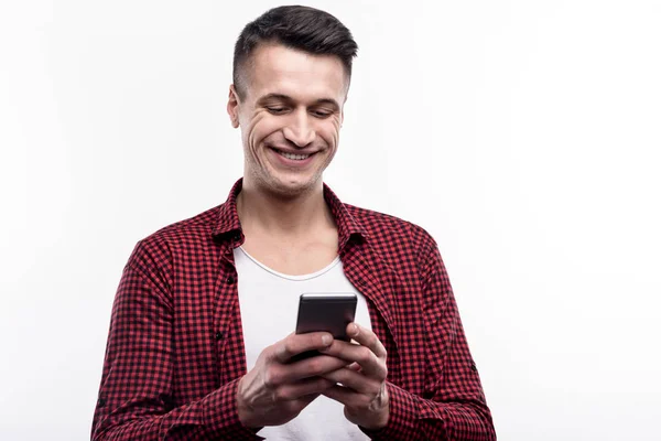 Encantador homem mensagens de texto alguém através de seu telefone — Fotografia de Stock