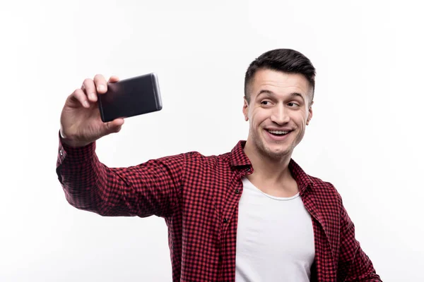 Joyeux jeune homme en chemise à carreaux prenant selfies — Photo