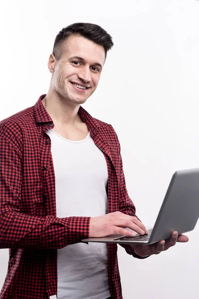 Laptop ile poz kontrol tişörtlü yakışıklı adam — Stok fotoğraf