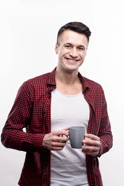 Jovem alegre na camisa verificada segurando xícara de café — Fotografia de Stock