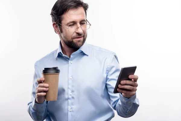 Agradable hombre mensajes de texto y la celebración de la taza de café — Foto de Stock