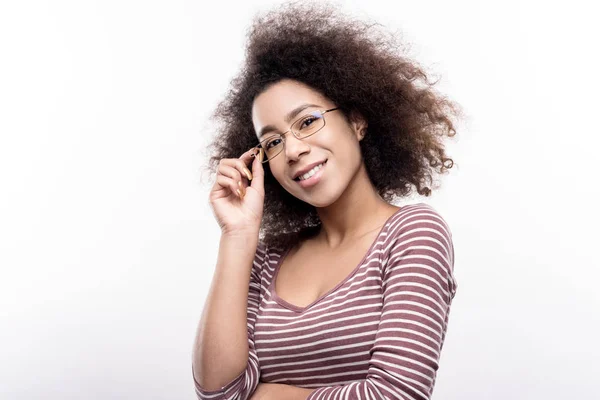 Curly-haired young woman adjusting her eyeglasses — Stock Photo, Image