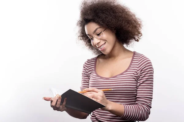Curly-haired young woman taking notes — Stock Photo, Image