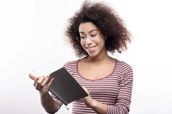 Jolie jeune femme aux cheveux bouclés écrivant dans le planificateur quotidien — Photo