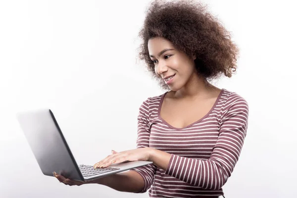 令人愉快的卷发年轻妇女在笔记本电脑上工作 — 图库照片