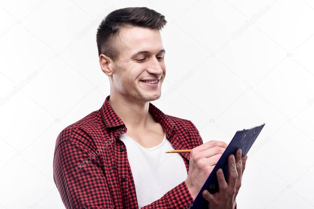 Charming young man making notes on sheet holder