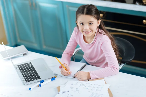 Chica inspirada haciendo su tarea y sonriendo —  Fotos de Stock