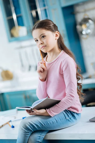 Thoughtful little girl sitting on the table — Stock Photo, Image