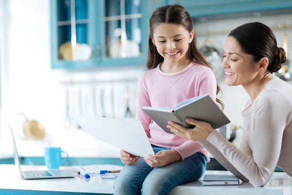 Inspiriertes Mädchen und ihre Mutter beim Durchblättern eines Buches — Stockfoto