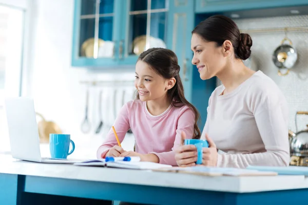 Glad tjej gör lektioner med hennes kärleksfull mamma — Stockfoto