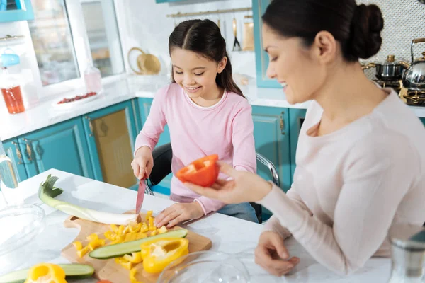 Alert girl smiling and chopping vegetables — Stock Photo, Image