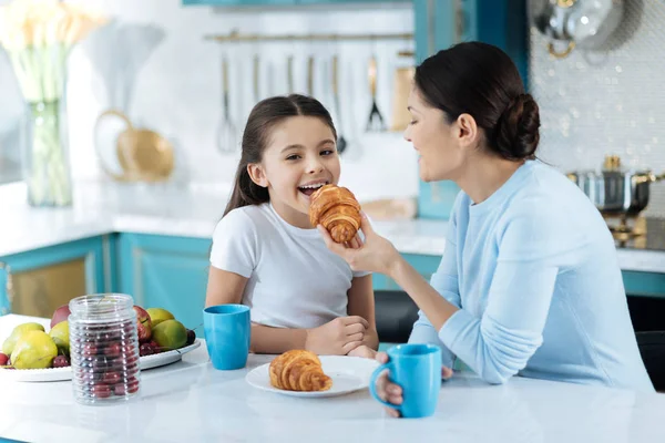 Exuberante menina comer biscoitos com sua mãe — Fotografia de Stock