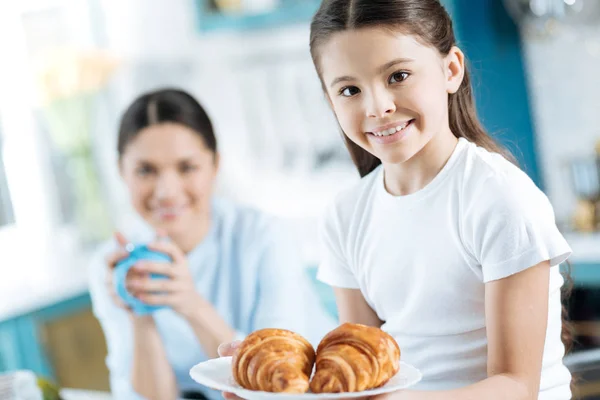 Sorrindo menina segurando um prato com croissants — Fotografia de Stock