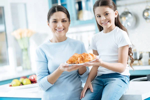 Sorrindo menina e sua mãe segurando um prato com croissants — Fotografia de Stock