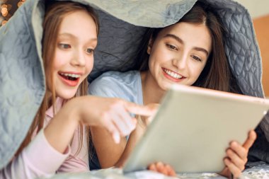 Battaniyenin altında yalan video izlerken iyimser kız kardeş