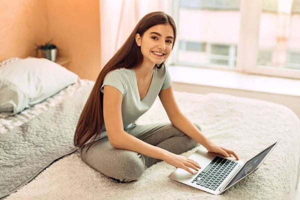 Приємна дівчина-підліток використовує свій ноутбук для навчання — стокове фото