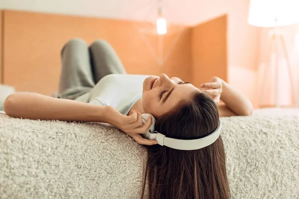 Bastante adolescente acostada en la cama y escuchando música —  Fotos de Stock