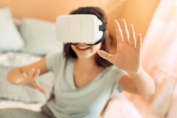 Bastante adolescente sentada en la cama y probando los auriculares VR —  Fotos de Stock