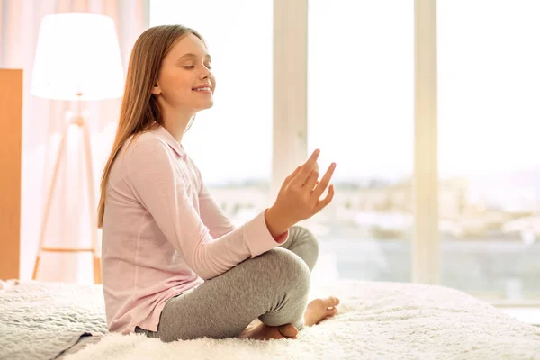 Piacevole adolescente che pratica yoga sul letto — Foto Stock