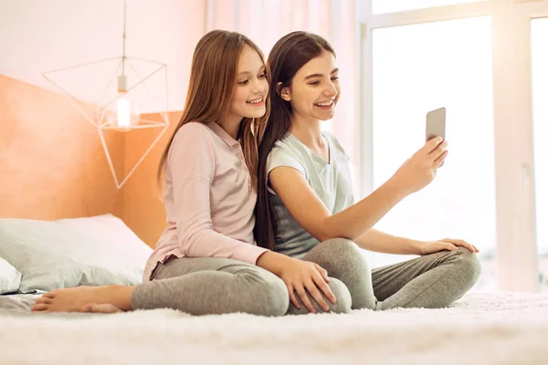 Duas irmãs fofas tirando selfies na cama — Fotografia de Stock