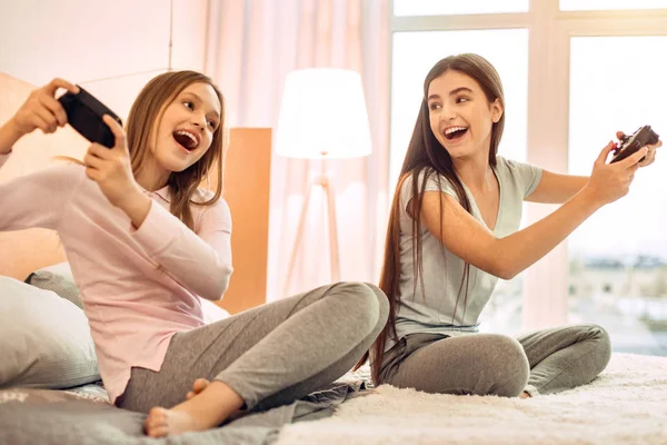 Upbeat teenage sisters playing video games emotionally — Stock Photo, Image