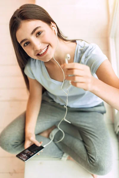 Vista superior de la chica adolescente agradable que ofrece un auricular —  Fotos de Stock