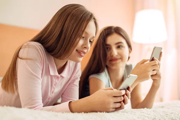 Pleasant girl watching her younger send messages — Stock Photo, Image