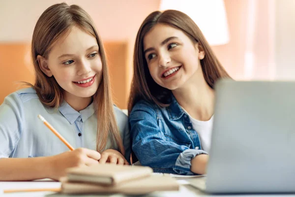 Alegre chica viendo su más joven hermana estudio —  Fotos de Stock