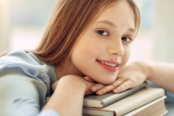 Nahaufnahme eines charmanten Mädchens, das sein Kinn auf Büchern ruht — Stockfoto