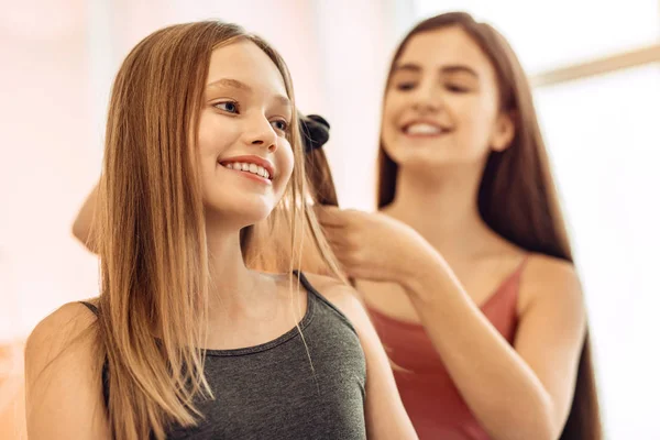 Pretty girl having her hair straightened by sister — Stock Photo, Image