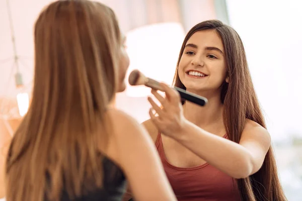 Sorrindo adolescente aplicando maquiagem para o rosto das irmãs — Fotografia de Stock