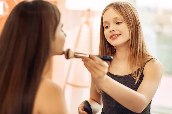 Pleasant girl applying powder to sisters chin — Stock Photo, Image