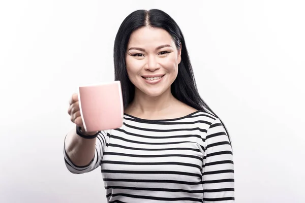 Vrolijke dark-haired vrouw overhandigen koffiemok — Stockfoto