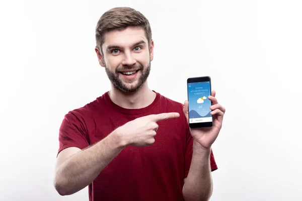Agradável homem sorridente mostrando aplicativo com previsão do tempo — Fotografia de Stock