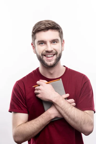 Homem alegre pressionando um planejador diário em seu peito — Fotografia de Stock