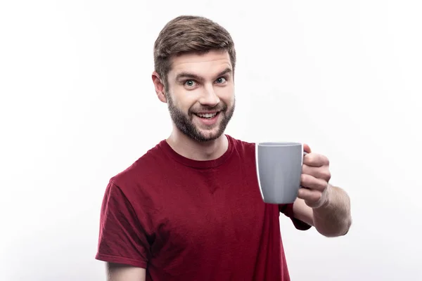 Lächelnder junger Mann, der eine Tasse Kaffee anbietet — Stockfoto