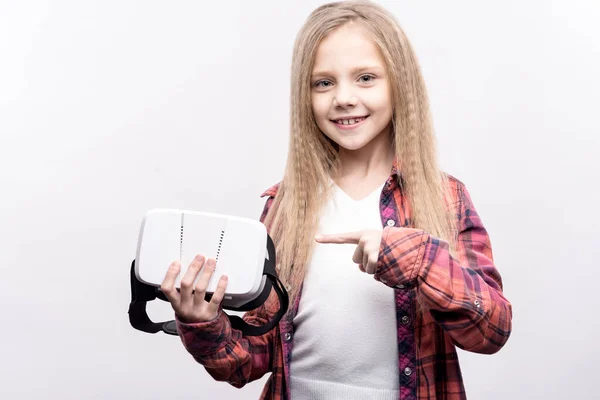 Mała dziewczynka, wskazując na zestaw wirtualnej rzeczywistości w jej ręce — Zdjęcie stockowe