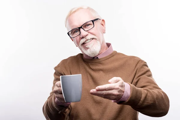 Miły starszy mężczyzna oferujący kubek kawy — Zdjęcie stockowe